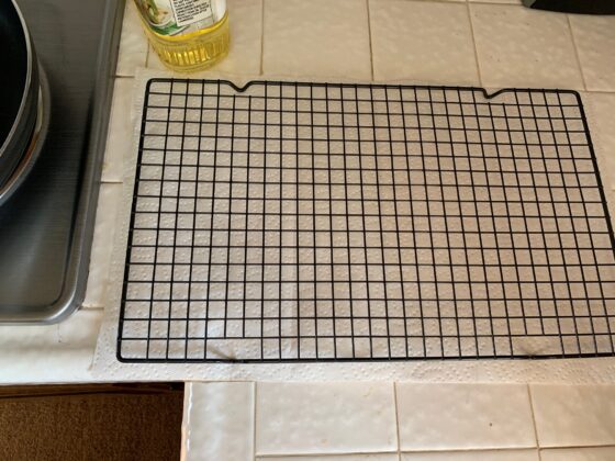 Bakers cooling rack resting on paper towels sitting next to frying pan