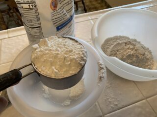Mixing bowls, measuring cup with flour and a bowl filled with flour.